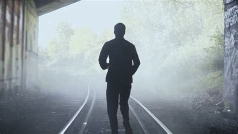 4K Man running away fast on foggy train tracks. Back view ...