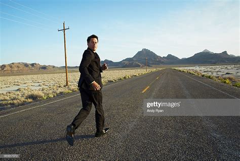 Businessman Running Down Desert Road Looking Back Stock ...