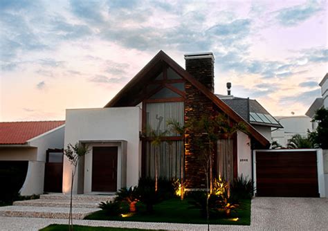 Casa de estilo moderno, com fachada com tons de branco, madeira e vidro