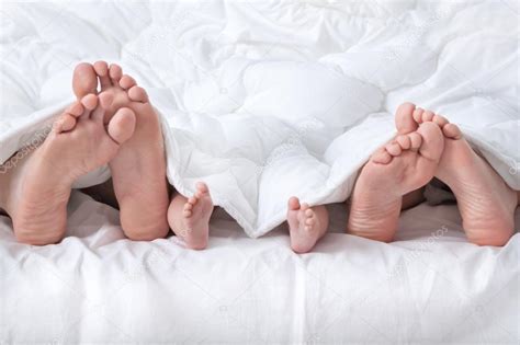 Couple avec bébé montrant pieds sous la couverture ...