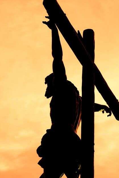 Cristo crucificado contra a luz durante o pôr do sol | Foto Premium