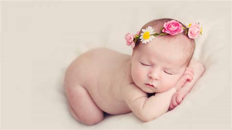 cute baby is sleeping on hands in bed having flowers crown ...