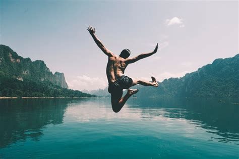 Hombre saltando de alegría por un lago | Foto Gratis
