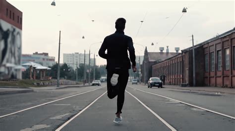 Man running in the middle of the street. Background shot. Slow motion ...