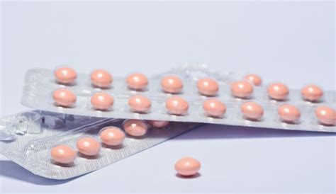 Manos de mujer abriendo píldoras anticonceptivas en la mano. la ...