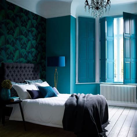 paredes azul intenso, empapelado con vegetación, cama en gris oscuro y ...