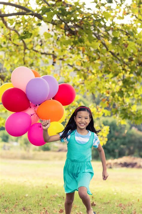 Retrato de niña sonriente jugando con globos en el parque ...