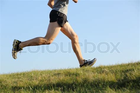 Side view of a jogger legs running on the grass with the ...