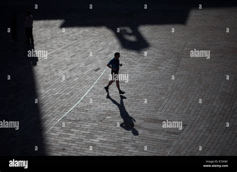 The shadow of a man running is cast on the street in the ...