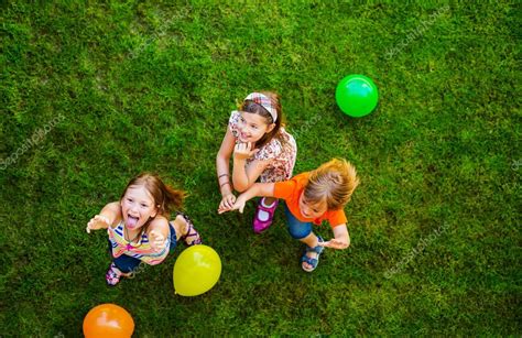 Tres feliz poco a los niños jugando con globos de colores ...