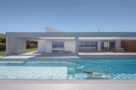 Una casa blanca y moderna junto a la playa en la costa griega con piscina