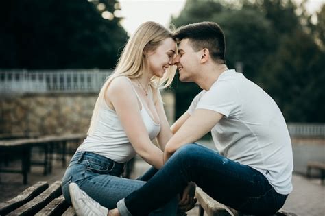 Una joven pareja de enamorados besándose en el banco en el parque ...