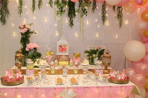 Una mesa dulce y una estructura de globos rosa y dorado ...